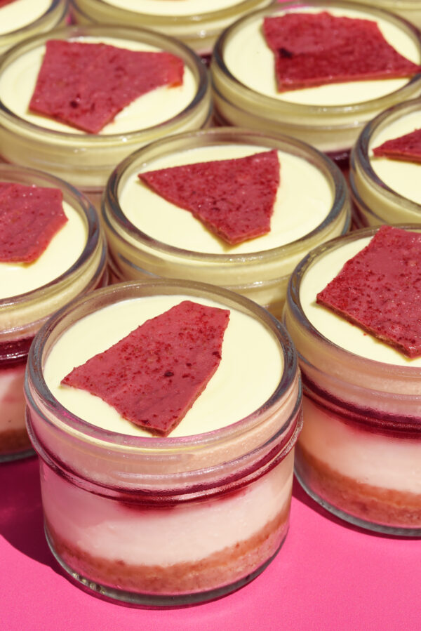 alt="A creamy Vanilla Cheesecake in a jar topped with Raspberry Compote, light Lemon Mousse made with freshly grated Lemon Peel and Limoncello, and finished with a crisp Raspberry Chocolate Crunch, made from scratch in San Antonio, Texas"