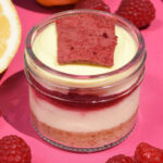 alt="A creamy Vanilla Cheesecake in a jar topped with Raspberry Compote, light Lemon Mousse made with freshly grated Lemon Peel and Limoncello, and finished with a crisp Raspberry Chocolate Crunch, made from scratch in San Antonio, Texas"