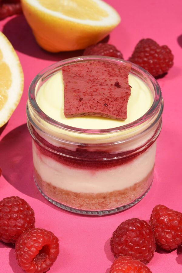 alt="A creamy Vanilla Cheesecake in a jar topped with Raspberry Compote, light Lemon Mousse made with freshly grated Lemon Peel and Limoncello, and finished with a crisp Raspberry Chocolate Crunch, made from scratch in San Antonio, Texas"