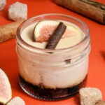 alt="Layered cheesecake jar made from scratch in San Antonio — starting with an Oreo crust, chai cheesecake, butterscotch crunch, silky butterscotch mousse, topped with fresh fig and a dark chocolate cigarette."