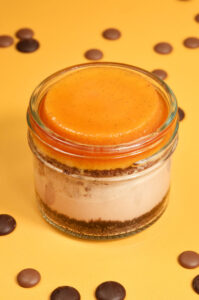 Cheesecake jar of Silky Milk Chocolate Cheesecake on an Oreo Crust, topped with Caramel-Soaked Chocolate Cake and rich, creamy Vanilla Flan. Made from scratch in San Antonio, Texas