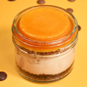 Cheesecake jar of Silky Milk Chocolate Cheesecake on an Oreo Crust, topped with Caramel-Soaked Chocolate Cake and rich, creamy Vanilla Flan. Made from scratch in San Antonio, Texas