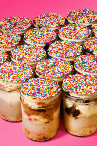 Viral Dot Cake Cheesecake: a layered cheesecake dessert with vanilla, chocolate, and cookies and cream cheesecake, birthday cake, chocolate cake, vanilla cream cheese buttercream, and a crunchy sprinkle shell made from scratch in San Antoni, Texas